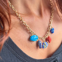 Under the sea charm necklace styled on model, displaying turquoise fish, coral shell, and tropical fish charms - one of a kind statement necklace
