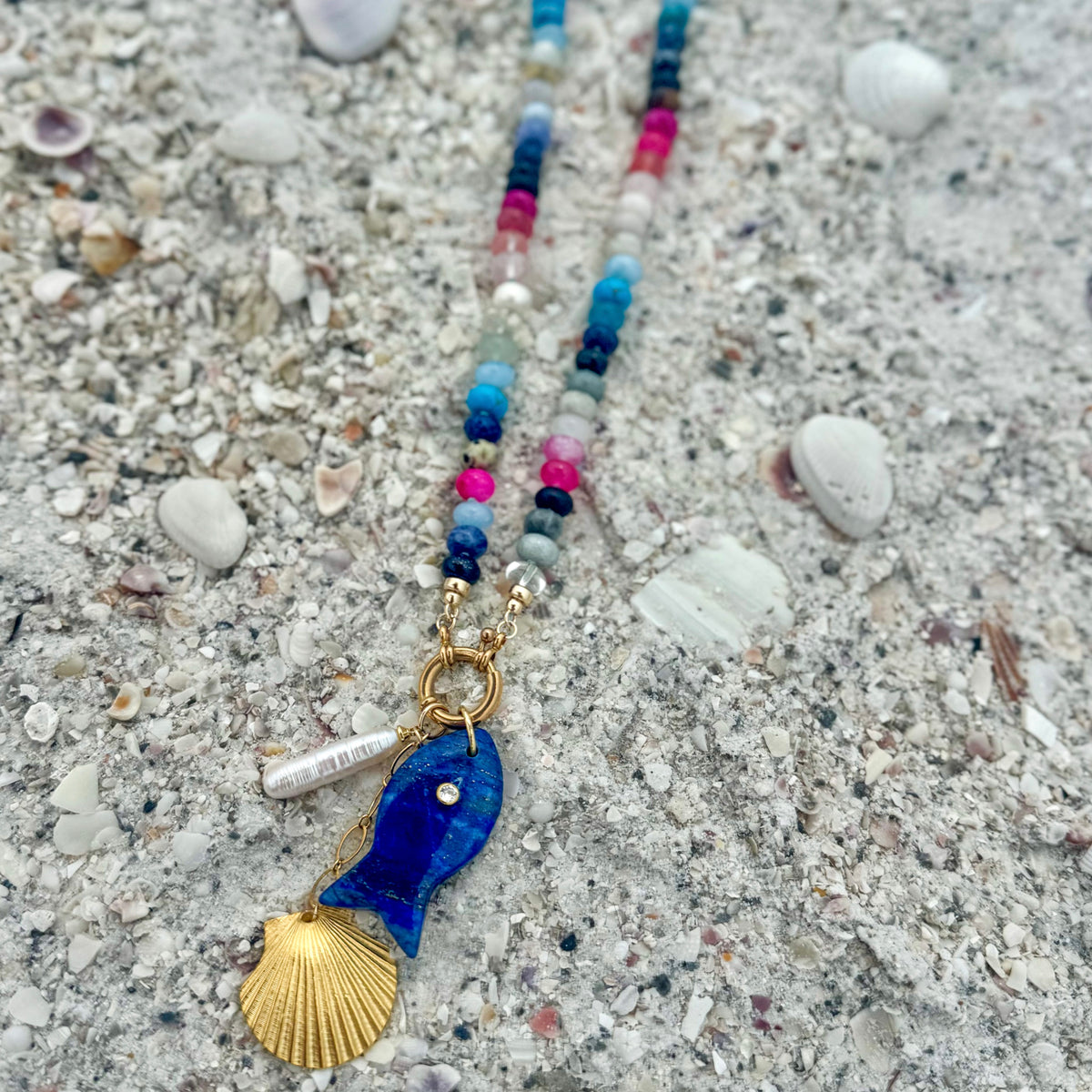 Tempest Necklace unique beaded design displayed on sandy beach surface with natural shells - one of a kind coastal inspired jewelry