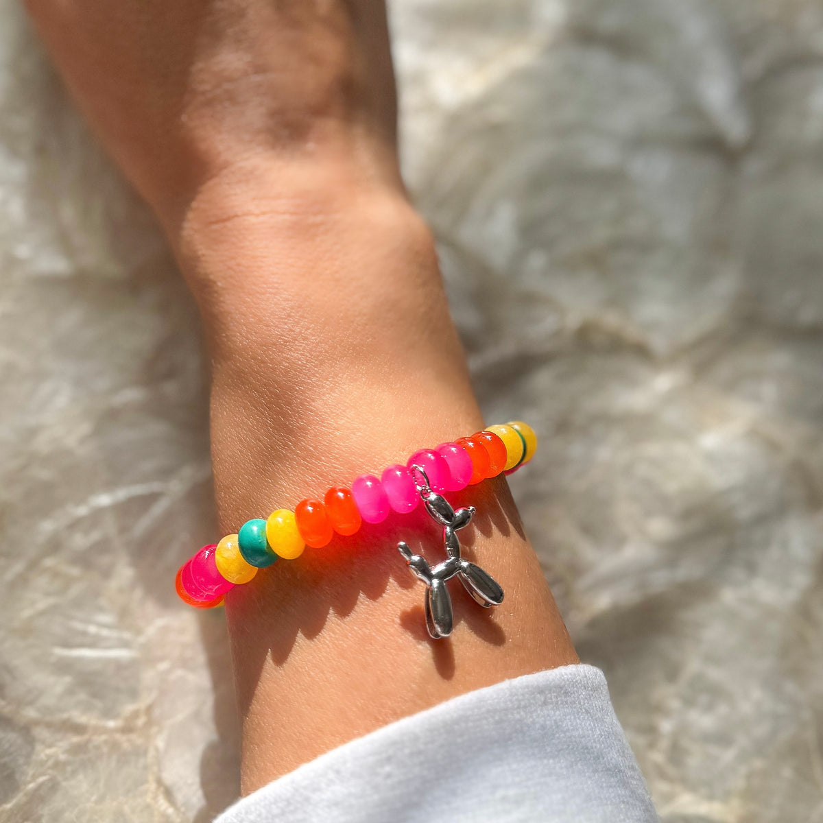 Carnival Candy colorful beaded stretch bracelet worn on wrist with rainbow translucent beads and silver balloon animal charm