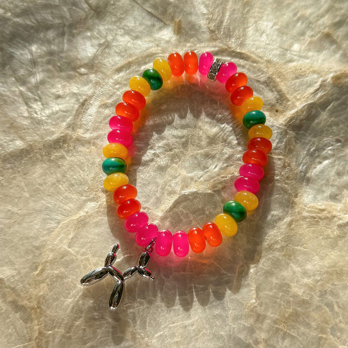 Carnival Candy 7 inch stretch bracelet with multicolored translucent beads pink orange yellow green blue and silver balloon animal charm on marble surface