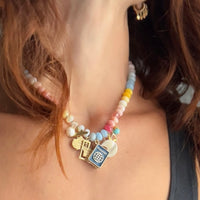 Colorful beaded necklace with travel charms worn by a model