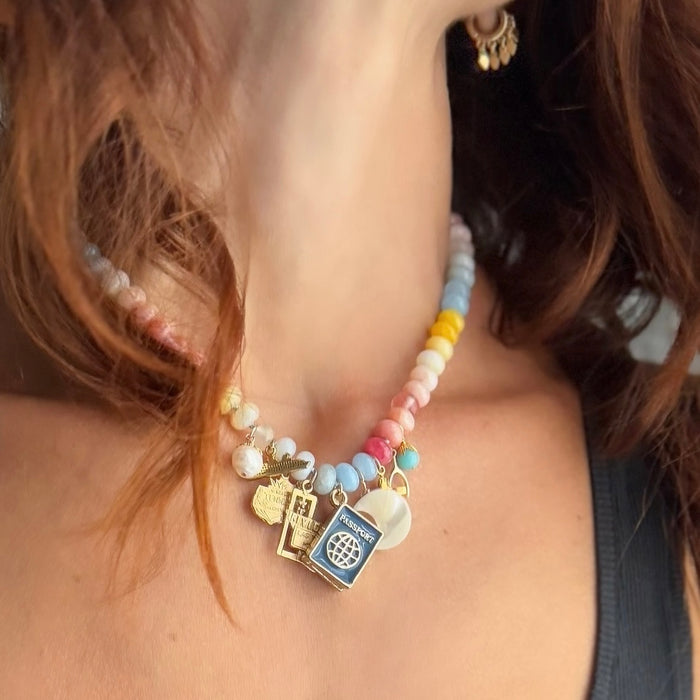 Colorful beaded necklace with travel charms worn by a model
