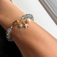 Detailed view of gold filled celestial charms star sun pearl and magnetic clasp on handcrafted rainbow fluorite bracelet