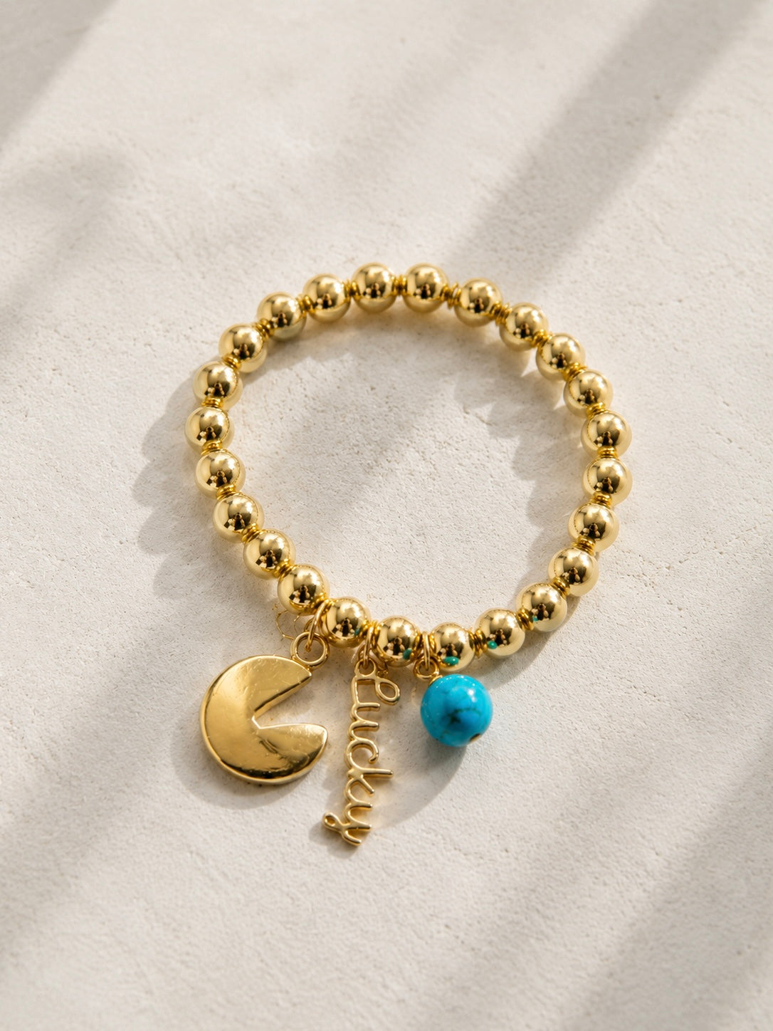 Gold tone hematite stretch bracelet with fortune cookie charm, Lucky script charm, and blue howlite stone bead — one of a kind handmade bracelet by Shop Lucky Charms