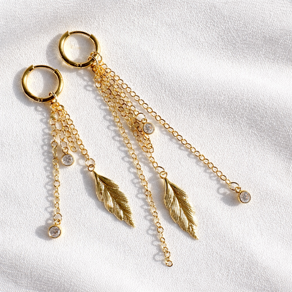 Pluma gold filled feather charm dangle earrings with cascading chains and crystal CZ accents on white satin background